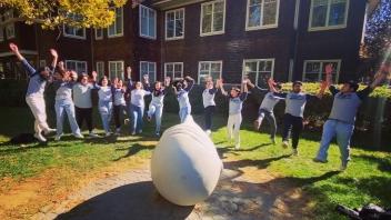 Students jumping for a picture around an egghead