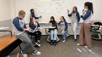 Students pose for a picture pretending like they are solving a math problem
