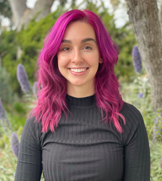 Alexandra (pink hair) smiling outdoors